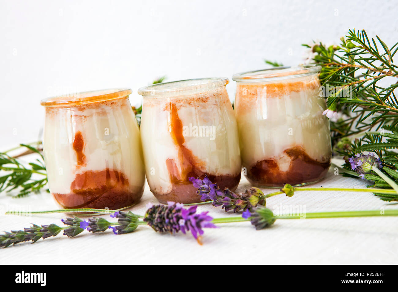 Trois yaourts naturels blancs avec de la confiture sur le fond de ce vase en verre Banque D'Images