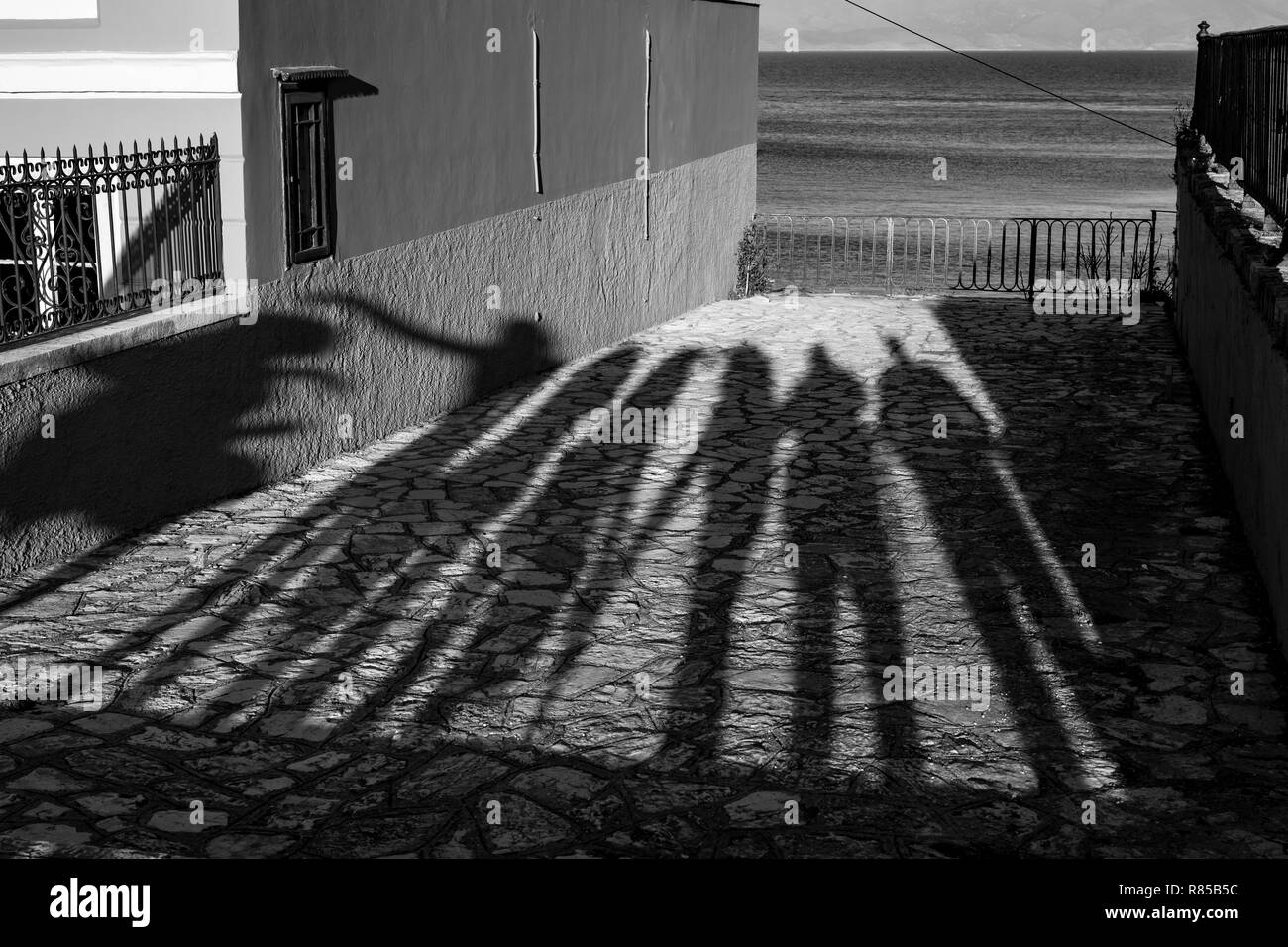 Les ombres de l'après-midi longue de sept personnes debout en face d'une plate-forme d'observation à Corfou, l'île de Kerkira, Grèce et la mer derrière la f métallique Banque D'Images