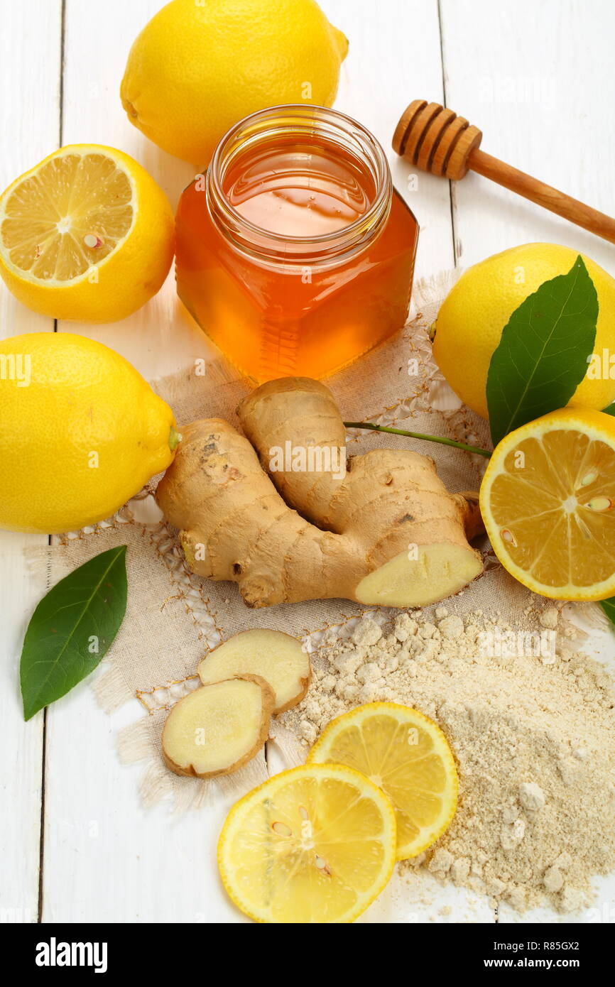 Racine de gingembre, citron et miel sur fond de bois blanc Banque D'Images