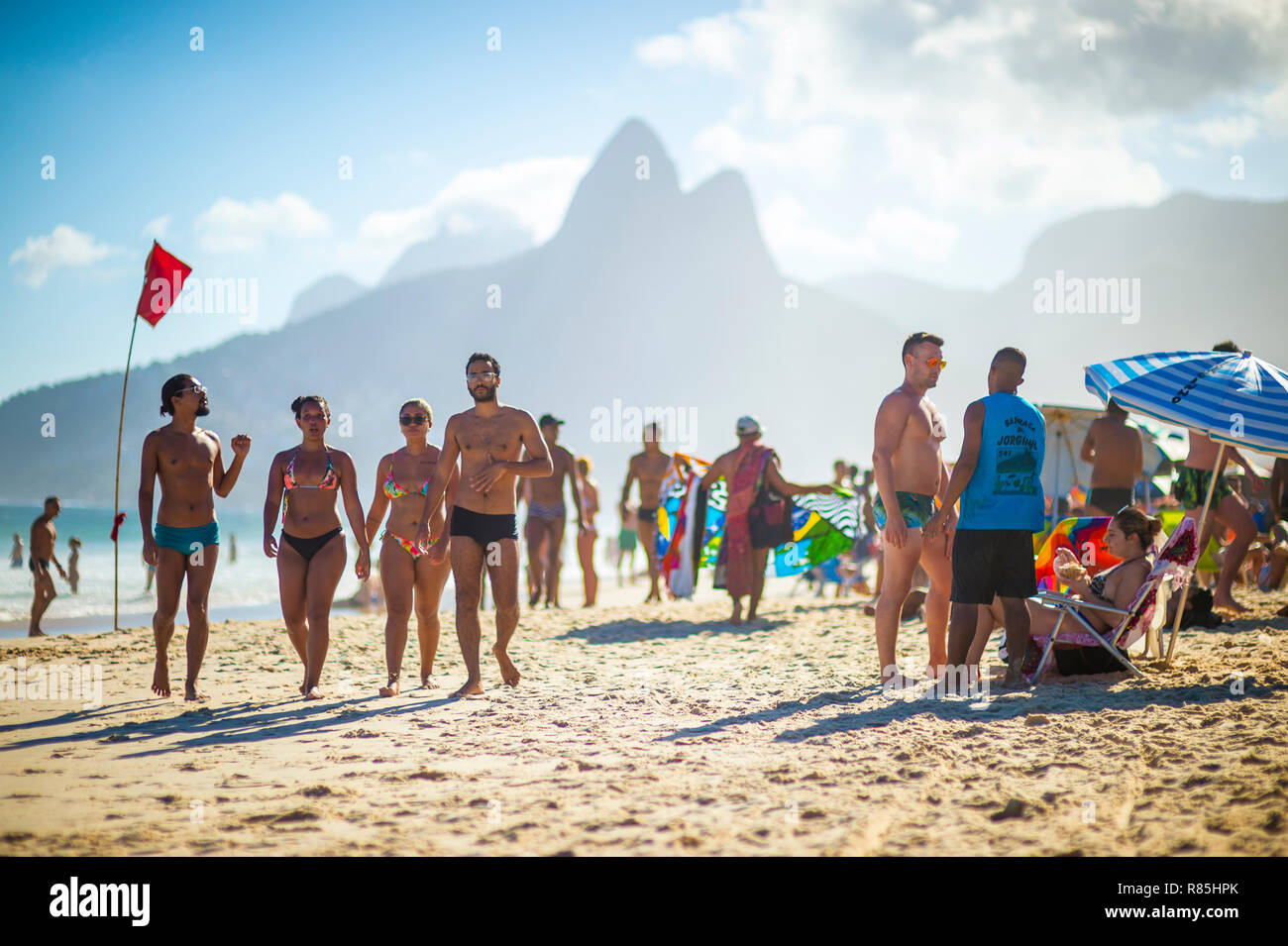 RIO DE JANEIRO - Février, 2018 : amateurs de promenade le long de la rive de la plage d'Ipanema sous un drapeau rouge avertissement de hautes vagues. Banque D'Images