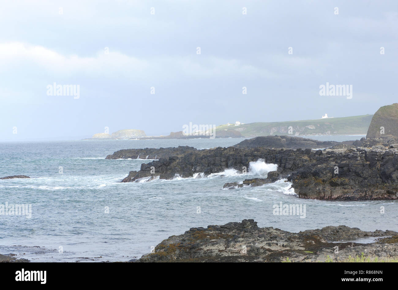 Les vagues se brisent sur les rochers de basalte de la côte en dessous des ruines du château de Dunsedick. Dunsedick, Comté D'Antrim, Irlande Du Nord, Royaume-Uni. Banque D'Images