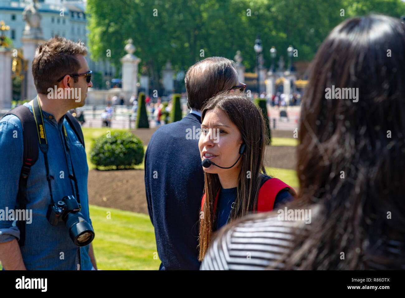 Les touristes à l'écoute de l'extérieur du guide de visite Buckingham Palace, London, UK Banque D'Images