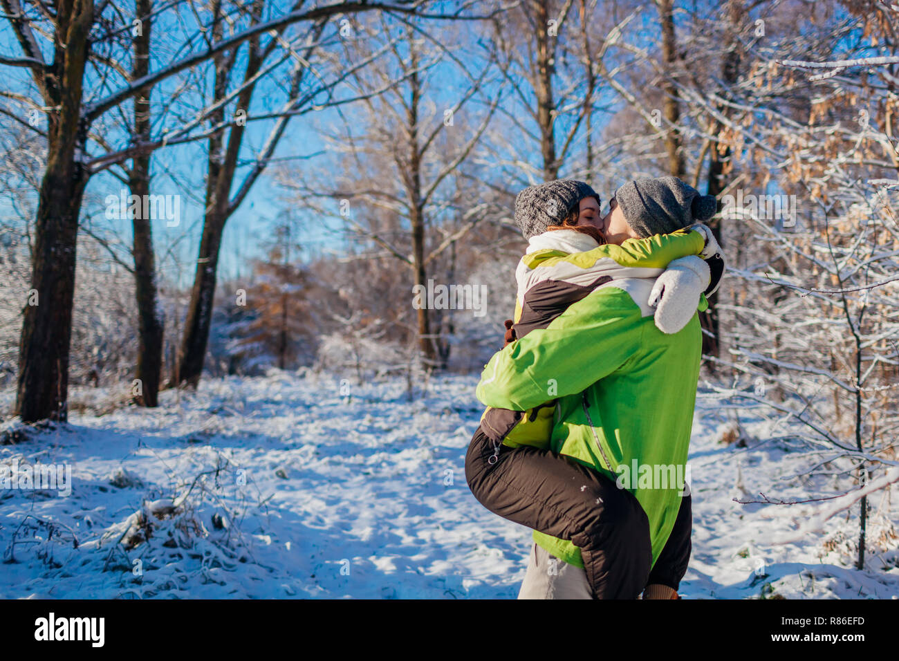 Couple heureux dans l'amour de marcher et s'étreindre dans la forêt d'hiver. Man holding amie et s'embrasser. Les jeunes s'amusant Banque D'Images