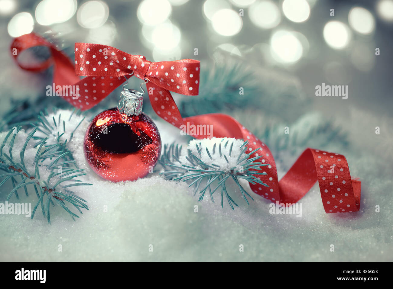 Boule de Noël rouge avec ruban à pois noeud sur un fond neutre avec des feux d'hiver noël Banque D'Images