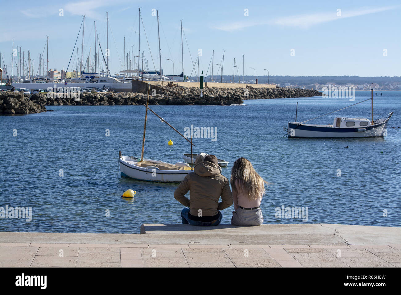 PALMA DE MAJORQUE, ESPAGNE - décembre 6, 2018 : jeune couple assis sur la jetée de Cala Estancia, un jour ensoleillé, le 6 décembre 2018 à Palma de Majorque, Spai Banque D'Images