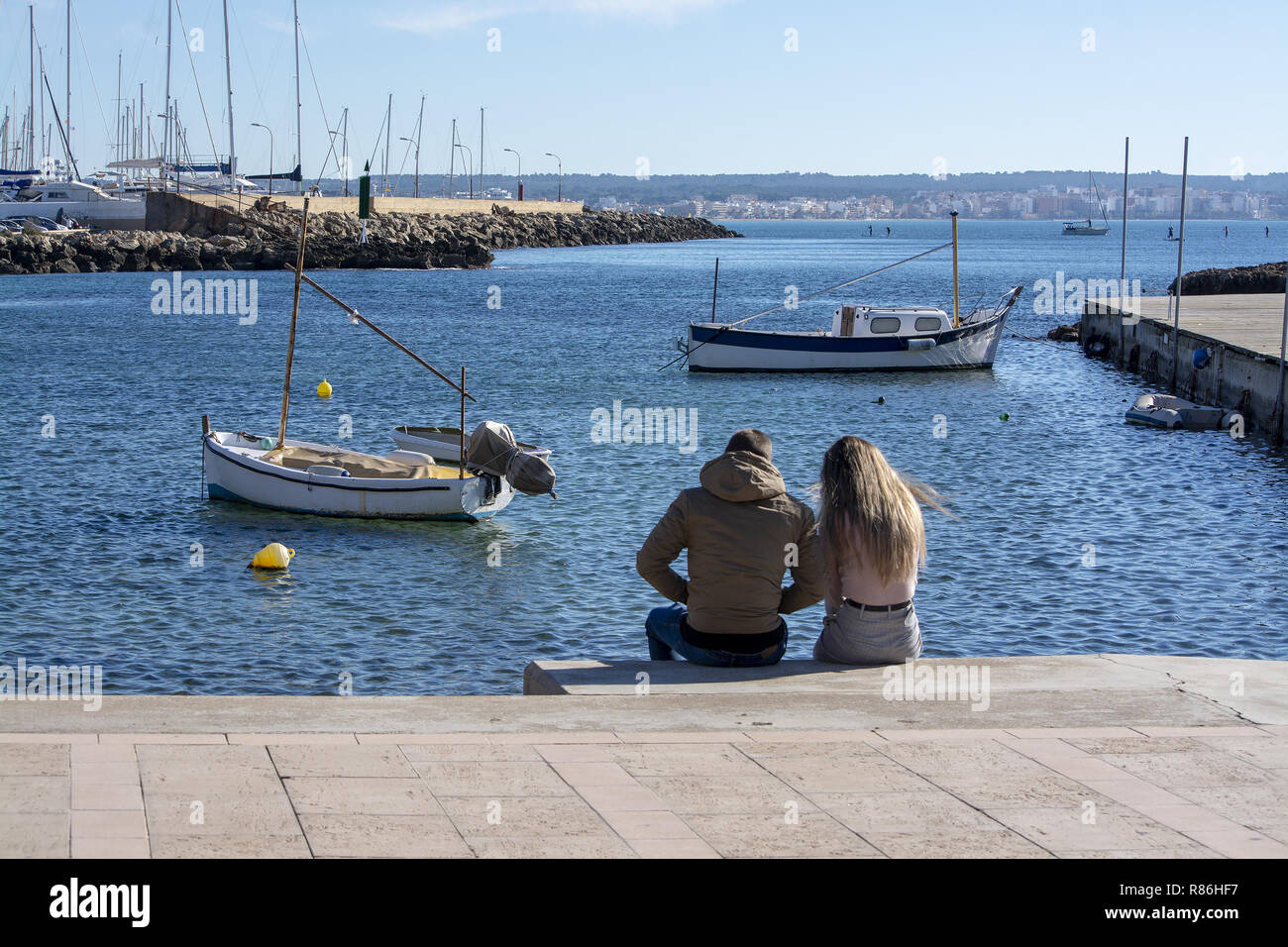 PALMA DE MAJORQUE, ESPAGNE - décembre 6, 2018 : jeune couple assis sur la jetée de Cala Estancia, un jour ensoleillé, le 6 décembre 2018 à Palma de Majorque, Spai Banque D'Images