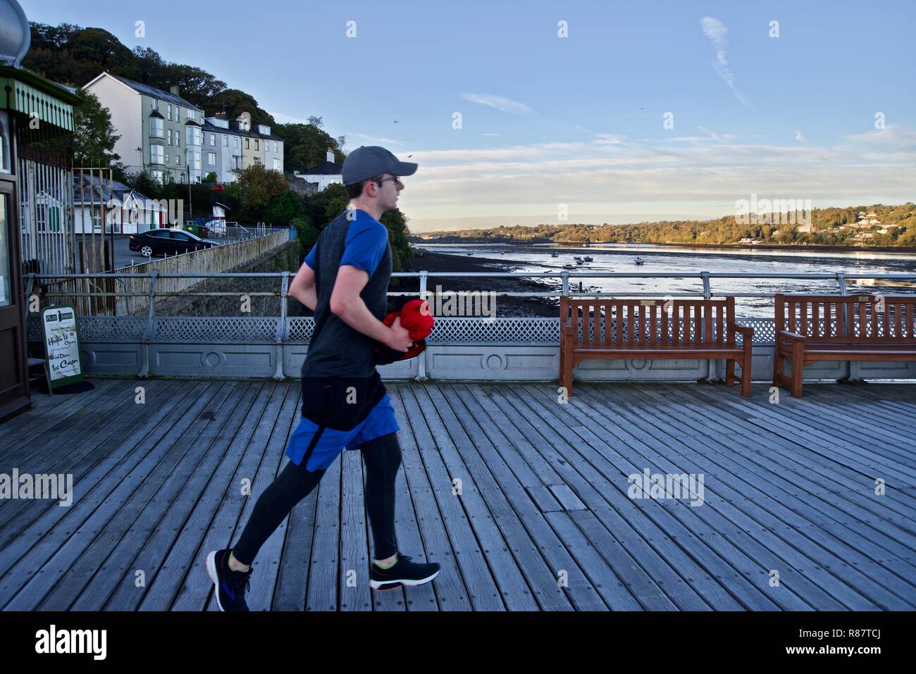 Un jeune homme jogger court le long de la jetée de Bangor à l'aube, Bangor, Gwynedd, au nord du Pays de Galles, Royaume-Uni Banque D'Images