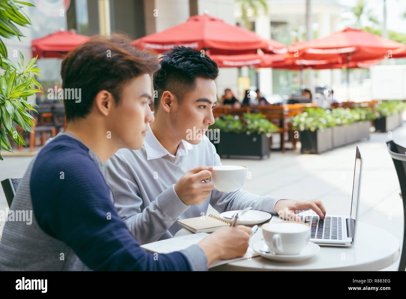 Deux jeunes hommes sont en pleine discussion dans un café. - Image Banque D'Images