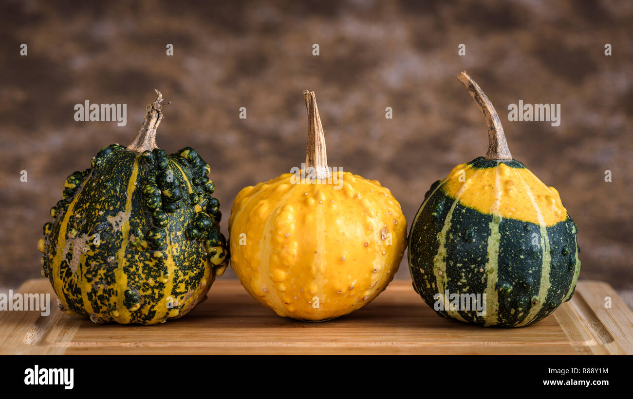 Trois citrouilles sur une table avec planche à découper en bois rustique et d'un arrière-plan. Banque D'Images