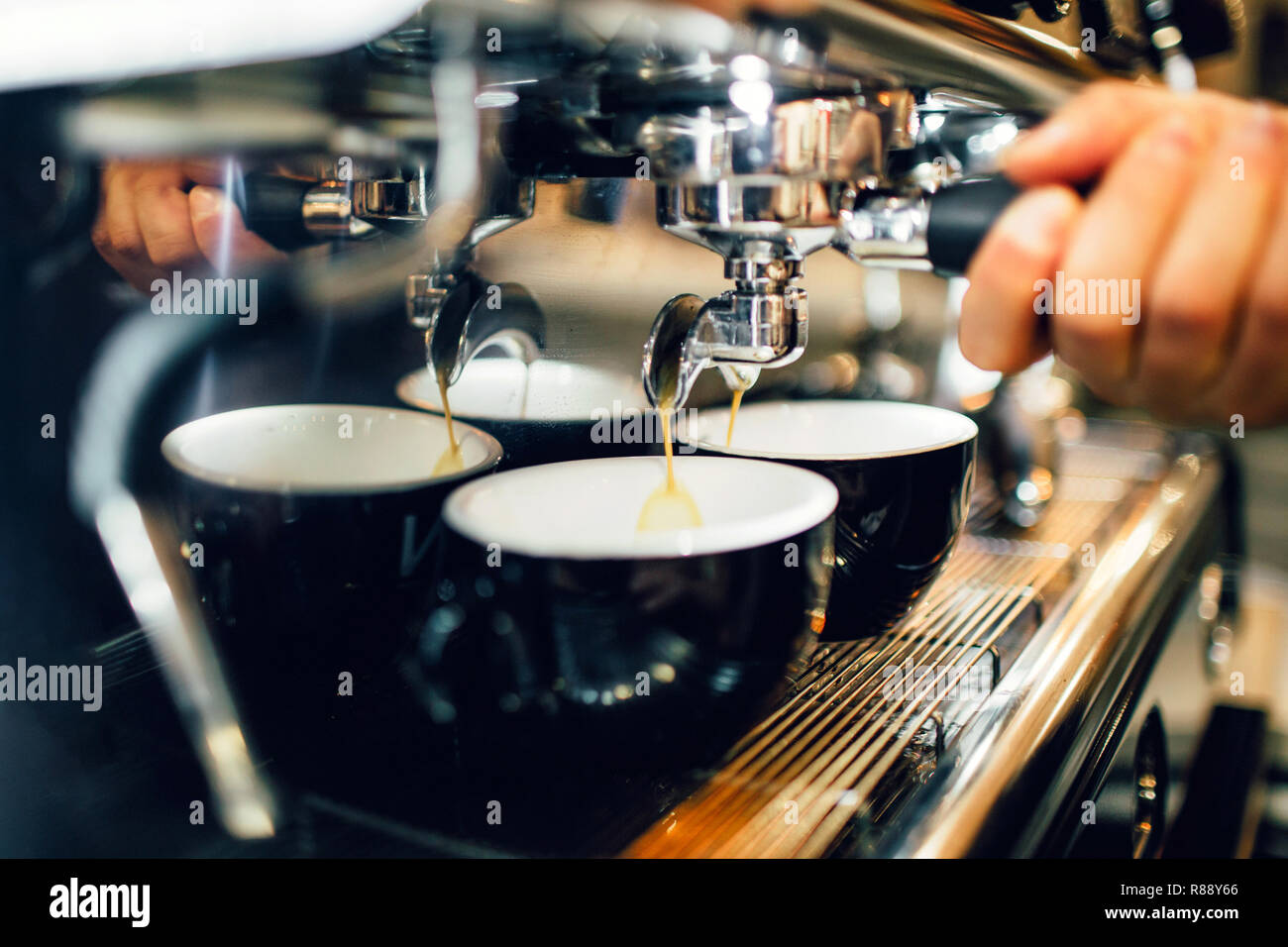 Close up et cut view of man's hand holding cezve à partir de la machine à café au-dessus de deux tasses. Verser le café est dans les tasses Banque D'Images