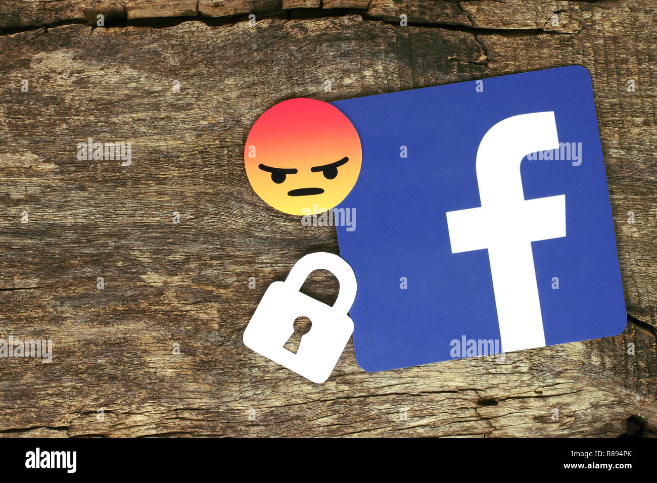 Kiev, Ukraine - le 04 mai 2017 : icône Facebook avec verrouillage et en colère sourire emoji imprimée sur du papier et placés sur l'ancien fond de bois. Banque D'Images