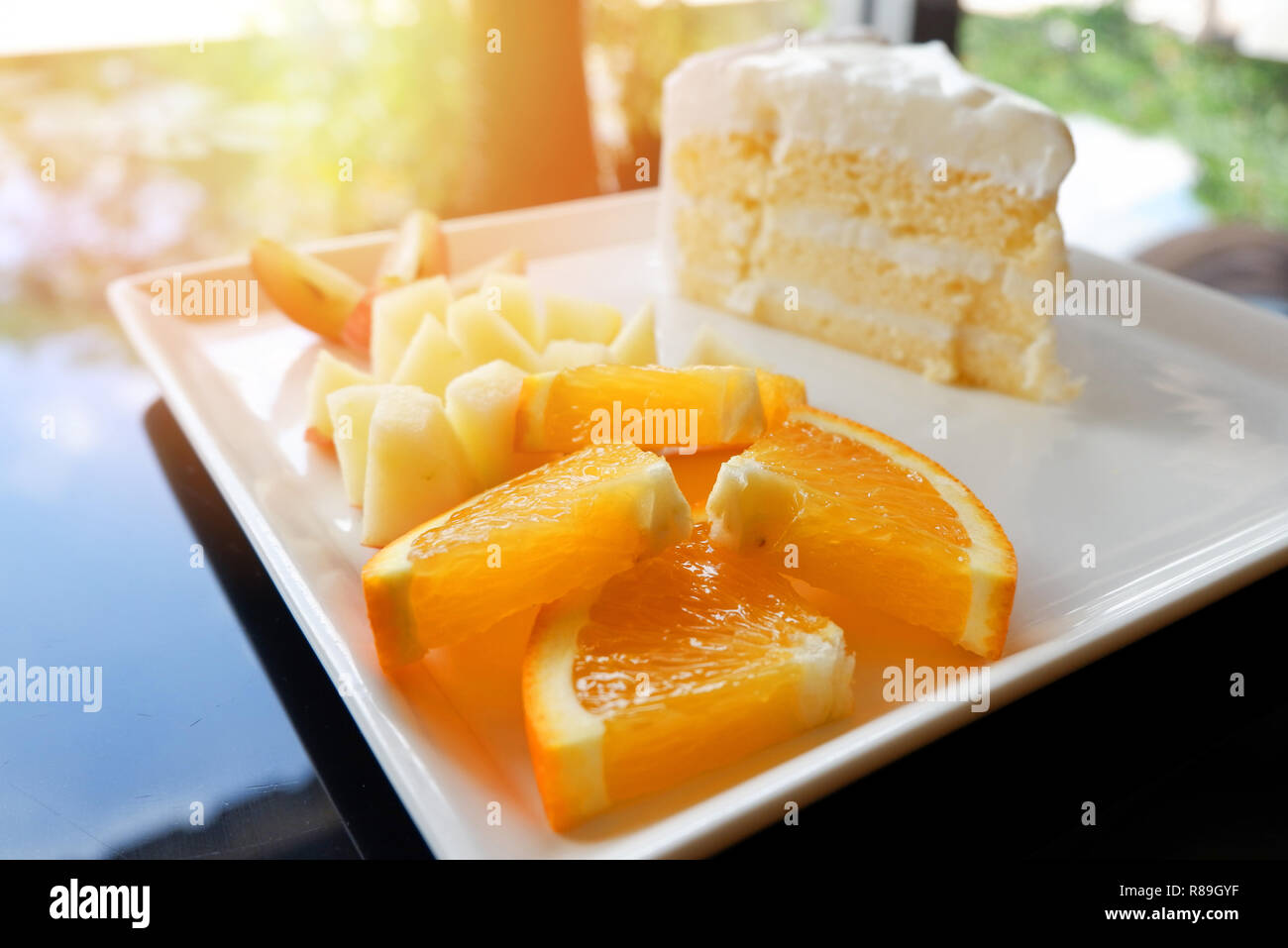 Lait et fruits coupe le gâteau sur une plaque blanche / close up of fresh orange raisin et pomme fruit tranche sur plateau avec crème dessert vanille Gâteau sur la table Banque D'Images