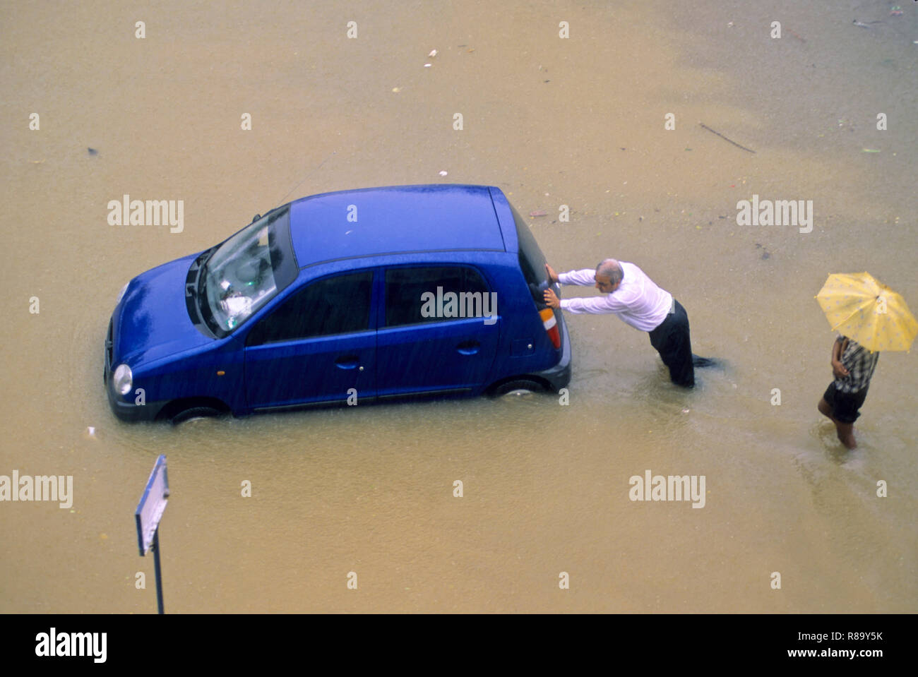 En raison des inondations à Heavy Rain, poussant l'homme voiture sur la route inondée, Bombay Mumbai, Maharashtra, Inde Banque D'Images