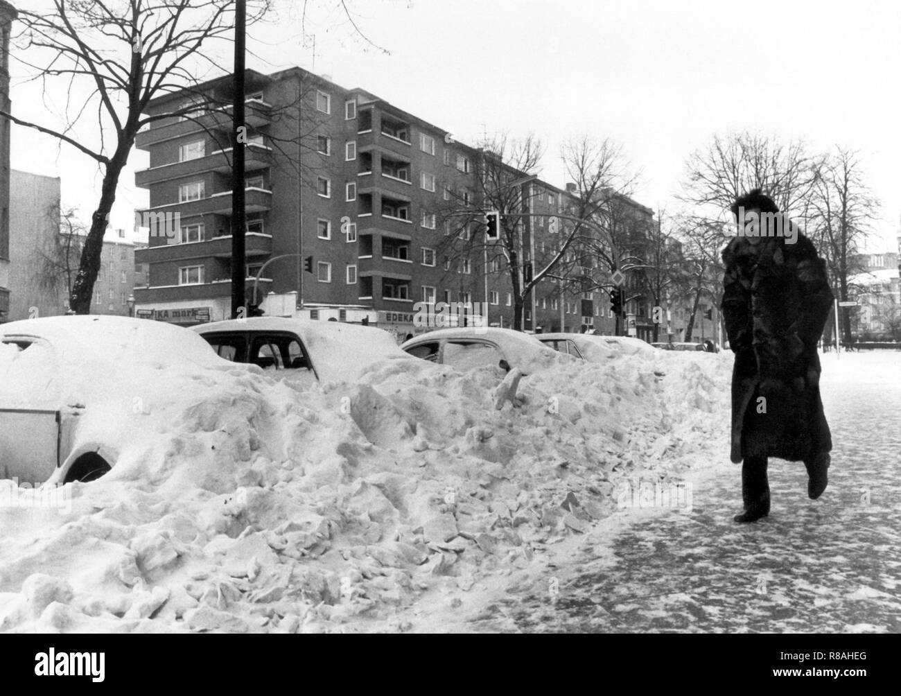 Un piéton fait son chemin sur la route glacée, tandis que les voitures en stationnement sont presque couverts par la neige, prise le 3 janvier 1979 à Berlin. La chute de température le 29 décembre 1978, conduit à un chaos de neige dans le nord de l'Allemagne, le nord de la RDA, le Danemark et le sud de la Suède. En partie le trafic et l'alimentation s'est effondré, localités ont été coupés du monde extérieur. Dans la République fédérale seulement, 17 personnes ont été tuées à cause de la neige le chaos. Dans le monde d'utilisation | Banque D'Images