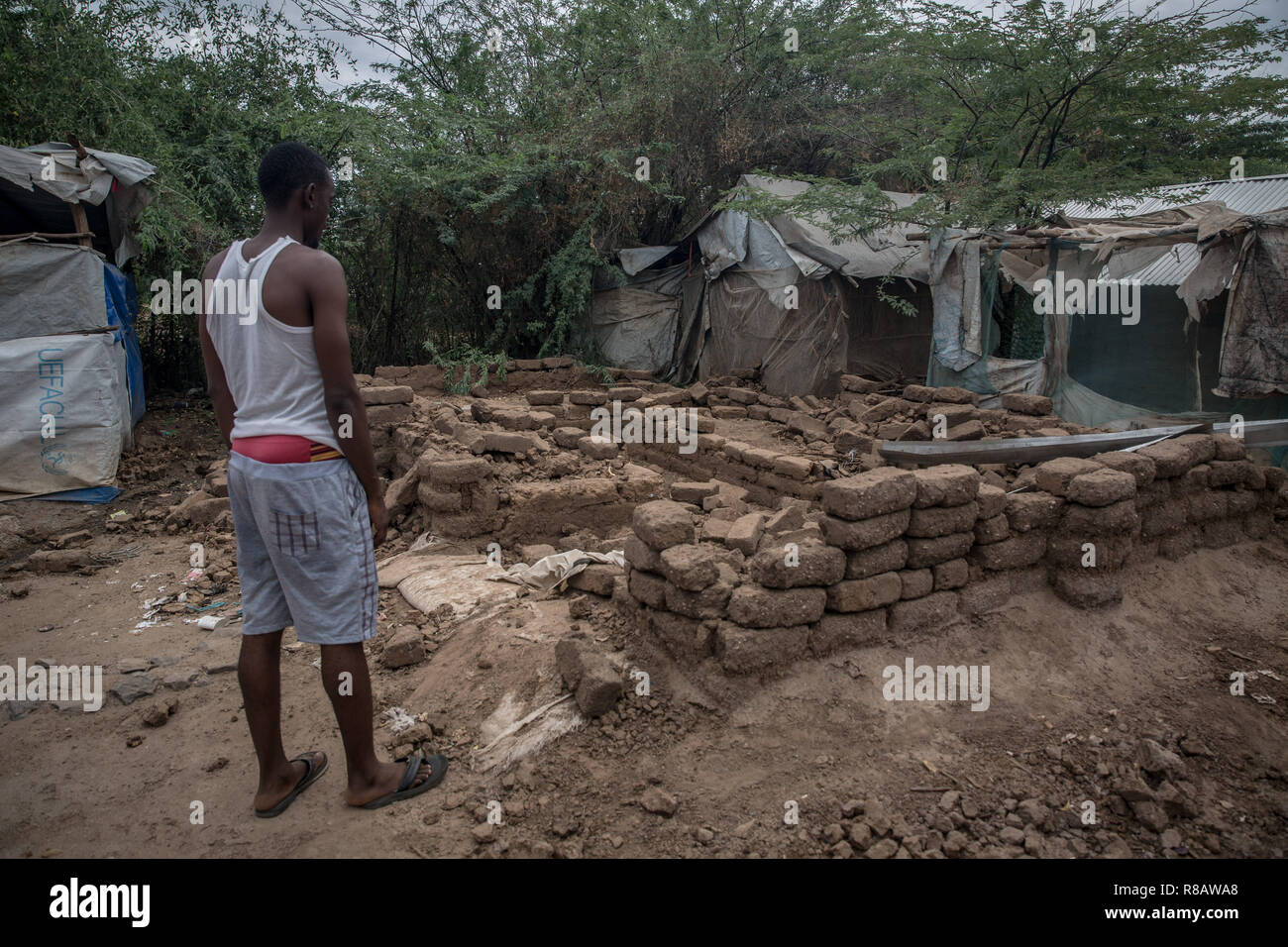 Un réfugié ougandais LGBT se tient juste en face de son logement, qui a été détruit par de fortes pluies, dans une section protégée du camp de réfugiés de Kakuma. Le camp de réfugiés de Kakuma, dans le nord-ouest du Kenya est le foyer de plus de 180 000 réfugiés et demandeurs d'asile, en provenance de pays dont l'Ouganda, Soudan du Sud, Soudan, Ethiopie, Tanzanie et en Somalie. Banque D'Images