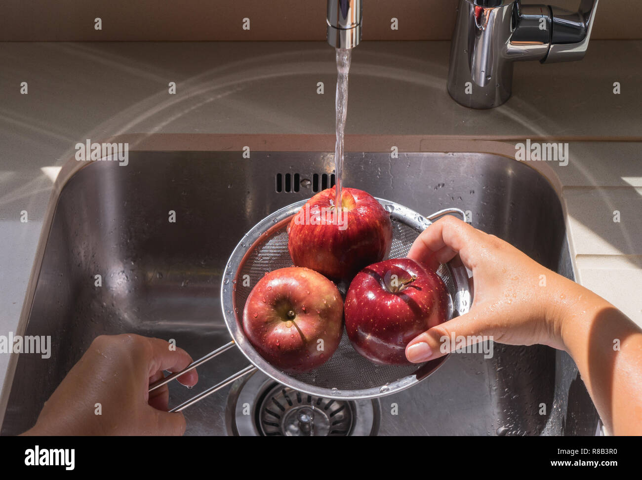Lave-mains femme pomme rouge dans l'eau de la crépine Banque D'Images