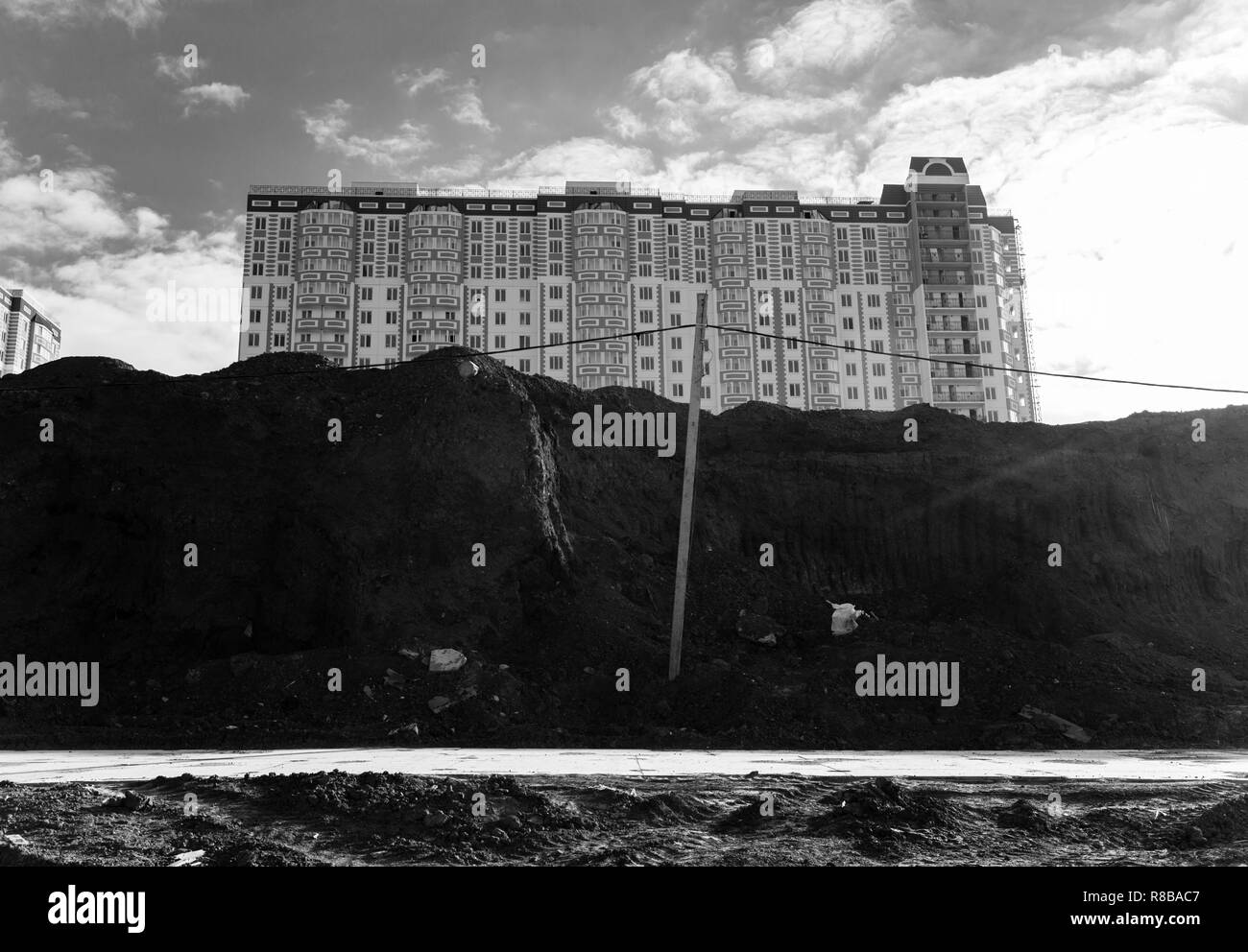 Vue du nouveau bâtiment résidentiel de plusieurs étages, debout sur le bord du site de construction. Photo en noir et blanc. Banque D'Images Vue du nouveau bâtiment résidentiel de plusieurs étages, debout sur le bord du site de construction. Photo en noir et blanc. Banque D'Images