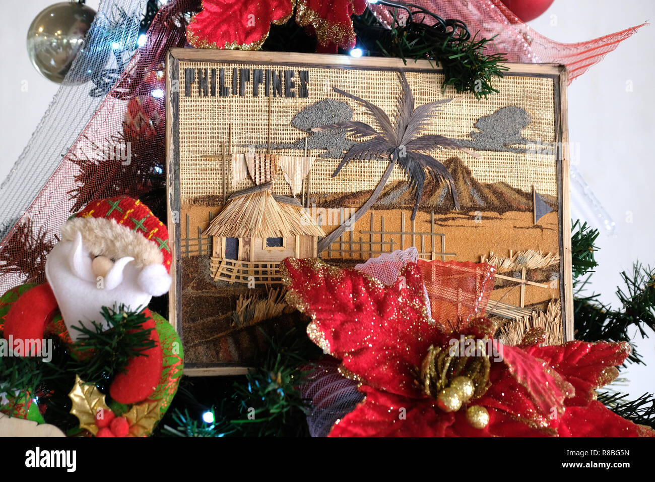 Une pièce encadrée, représentant une scène philippine classique avec une cabane nipa (habitation traditionnelle), décore un arbre de Noël Philippines Banque D'Images