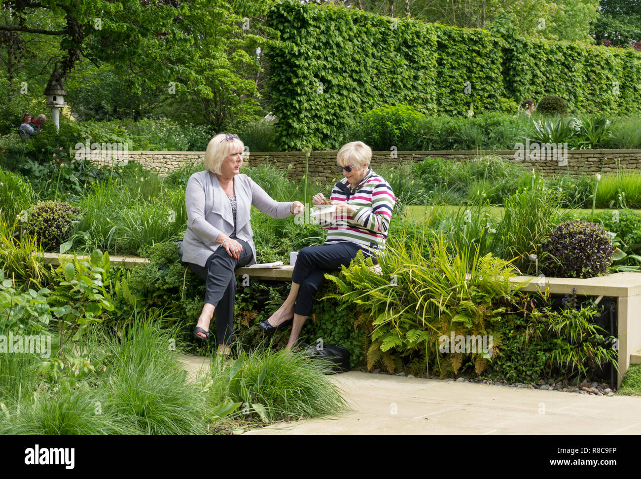 Deux femmes seniors, bénéficiant d'un thé l'après-midi, entouré de verdure, à l'ancien presbytère ouvrir sous le Jardin National Schéma ; Quinton, UK Banque D'Images