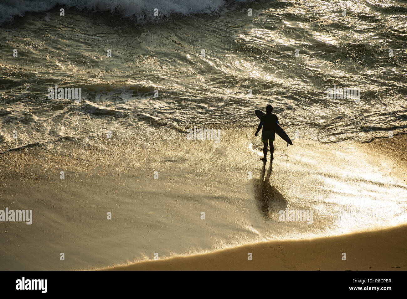 Un touriste avec son surf est sur le Varkala plage au coucher du soleil prêt à entrer dans la mer. L'Inde. Banque D'Images