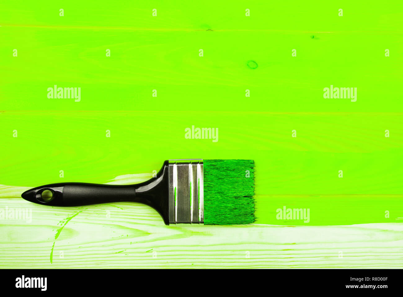 Brosse à manche noir sur vert d'ovni en bois peint la moitié du conseil. Concept de rénovation. Banque D'Images