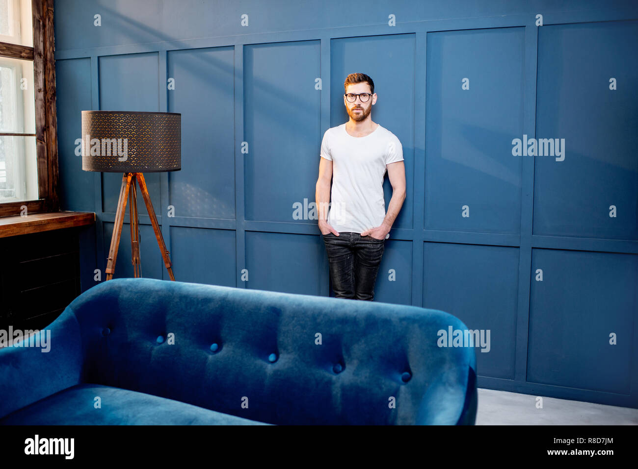 Portrait d'un homme en t-shirt blanc debout sur le mur bleu dans le luxe maison ou bureau intreior Banque D'Images