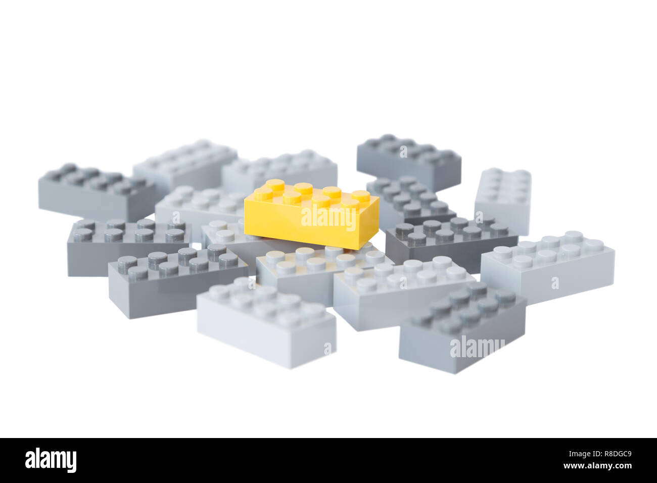 Tas de briques de construction jouet gris et un jaune lumineux au-dessus d'eux. Concept photo de se démarquer de la foule ou gris de masses. Isolé sur blanc. Banque D'Images