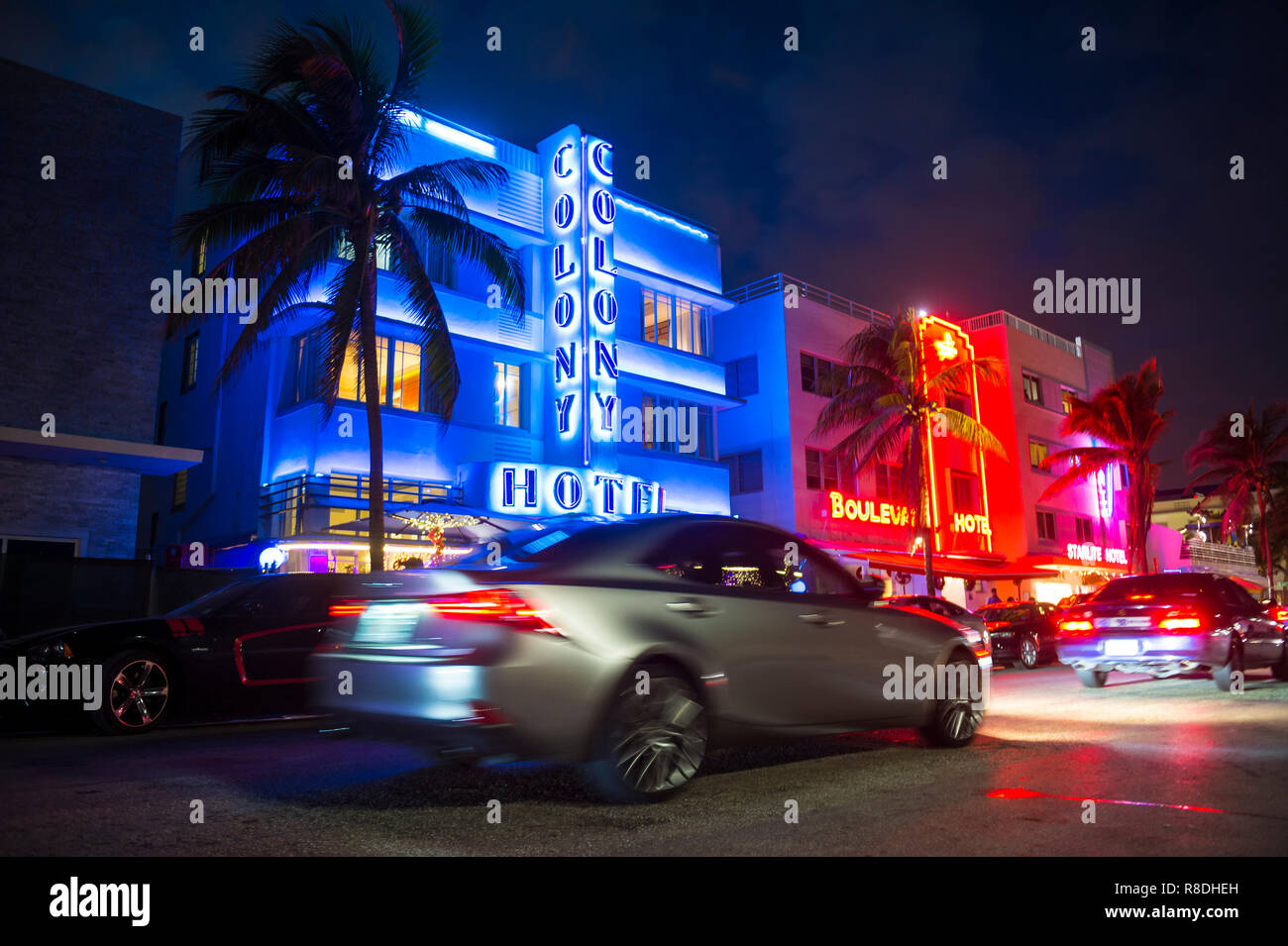 MIAMI - 08 janvier, 2018 : voitures de route passé l'iconique des enseignes au néon de couleur vive de l'Art Déco hôtels sur Ocean Drive à South Beach de nuit. Banque D'Images