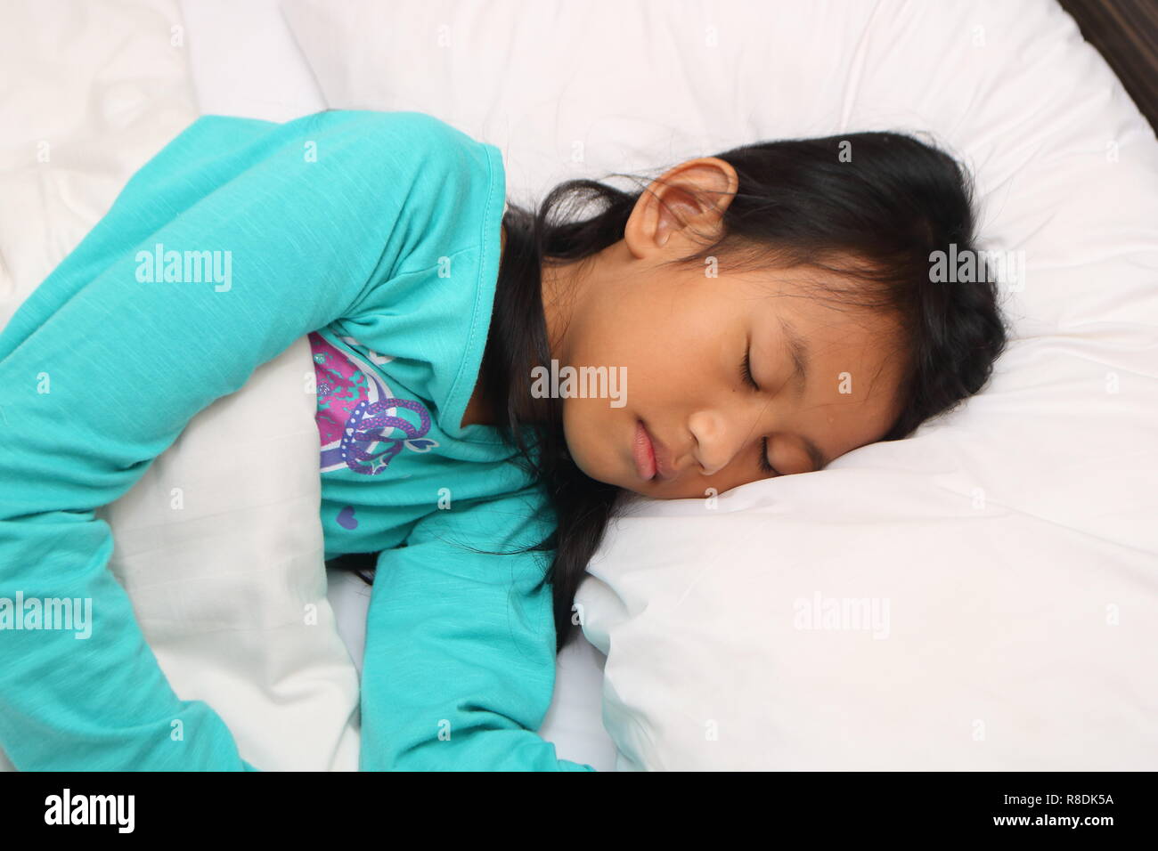 Vue latérale du peu d'Asian girl sleeping on bed Banque D'Images