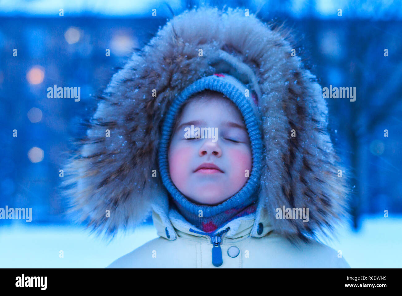 Petite fille dans la soirée d'hiver les captures des flocons de sur une période d'hiver, de la tuyère Banque D'Images