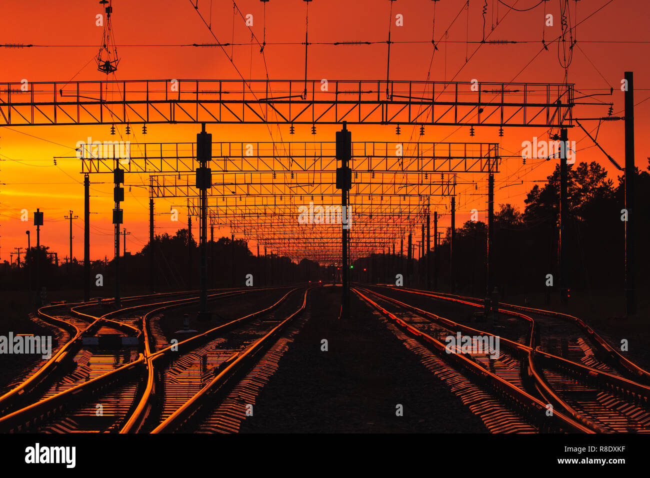 Silhouettes Sombres l'infrastructure ferroviaire en contre-jour coucher de soleil spectaculaire. Vue panoramique de fer dès aujourd'hui à la lumière du soleil. Transports et de la Trave Banque D'Images