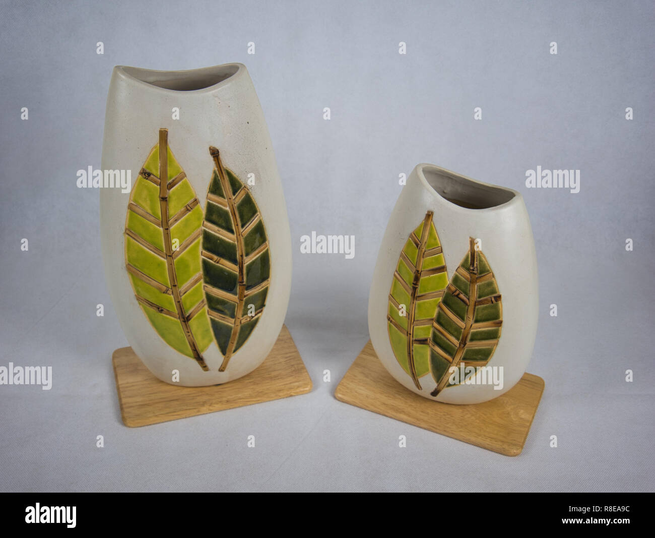 Deux vases de différentes tailles en terre cuite avec motif de feuille sur une planche en bois Banque D'Images