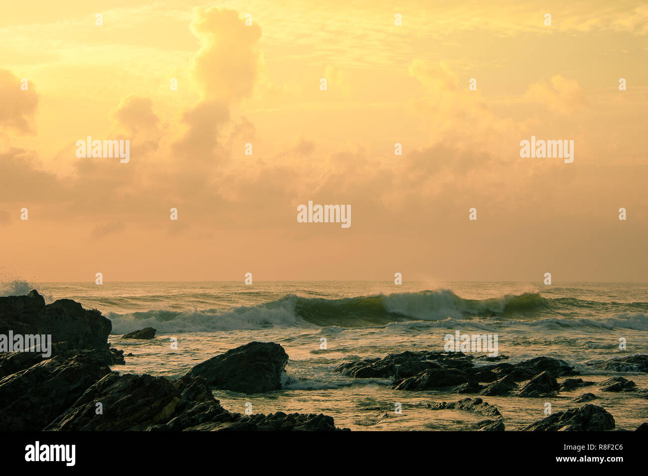 Le lever du soleil sur la mer de Chine du Sud, de l'est côte malaisienne. Vue pittoresque, soft Cotton Candy nuages, vagues se brisant le long du littoral rocheux, avant-plan Banque D'Images