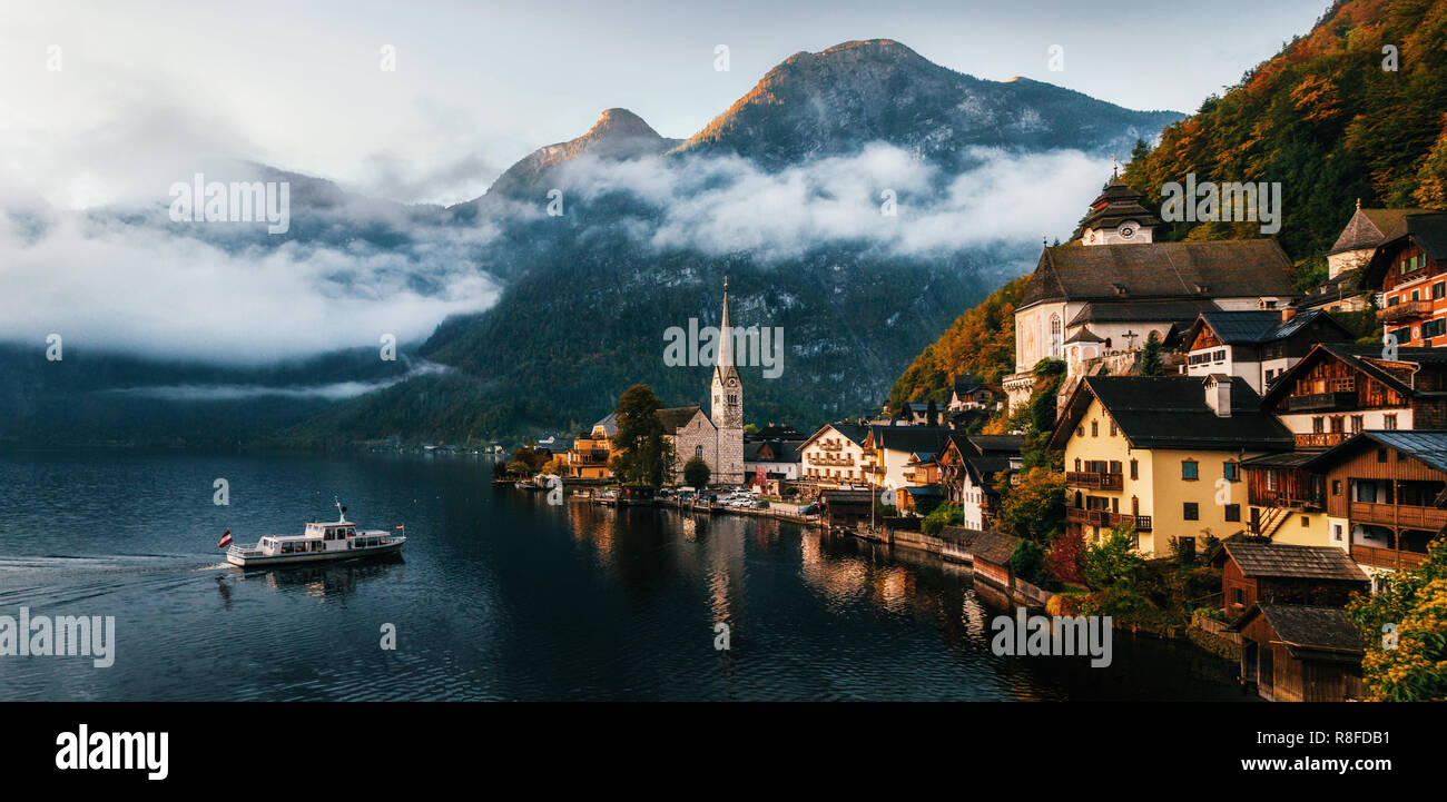 Bouilloire petit ferry arrive au quai de la ville de Hallstatt se reflétant dans le lac Hallstattersee dans Alpes autrichiennes en matin, région du Salzkammergut, Autriche Banque D'Images