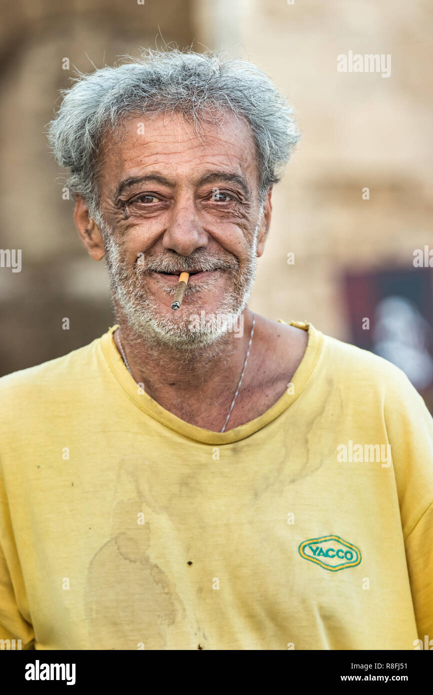 Rhodes, Grèce - 10 octobre 2018 : Portrait d'un homme mûr fumeurs avec les cheveux gris et sa barbe, heureux, qui travaille à l'orifice o Banque D'Images