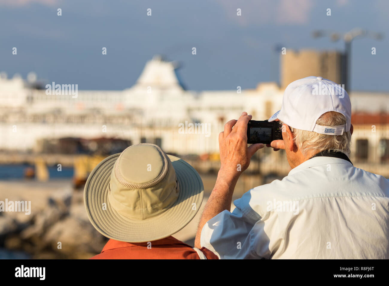 Rhodes, Grèce - 10 octobre 2018 : un couple de touristes prenant des photos avec un petit appareil photo numérique au port de Rhodes en Grèce. Banque D'Images