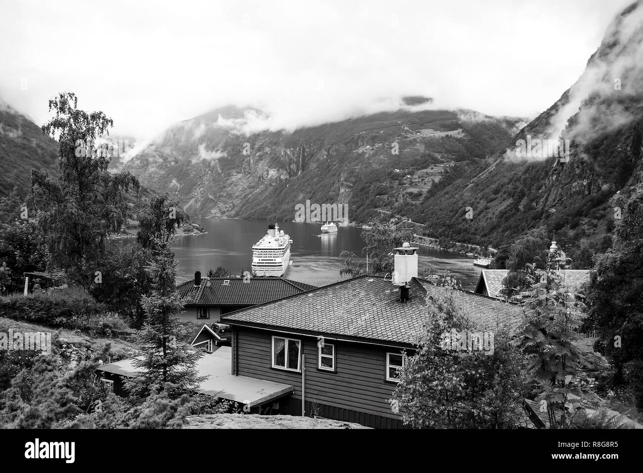 Geiranger, Norvège - le 25 janvier 2010 : aventure, découverte, voyage. Navire au fjord norvégien sur ciel nuageux. Paquebot dans port du village. Destination Voyage, tourisme voyage de vacances wanderlust Banque D'Images
