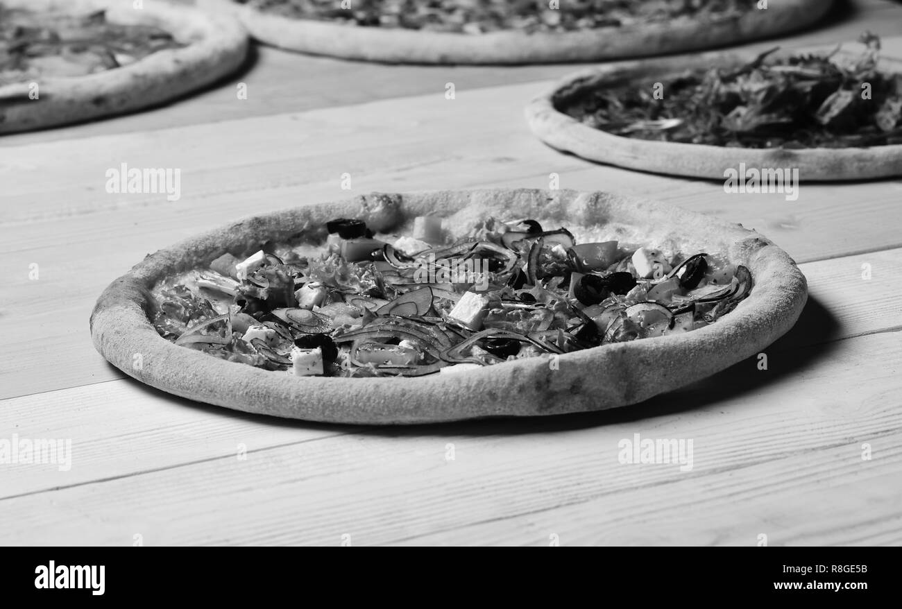 Plats à emporter avec bords croquants. Pizza grecque aux olives noires. Pizza aux tomates, fromage feta, salade et oignon rouge jaune sur fond de bois. La cuisine italienne et la livraison de nourriture concept Banque D'Images