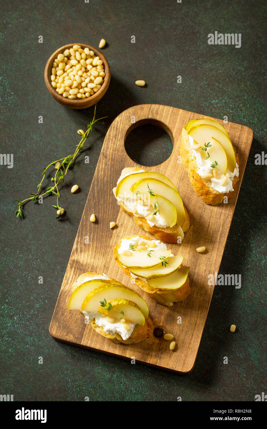 Antipasti des collations pour le vin. Brushetta avec fromage et poire servi sur une planche en bois rustique sur une table en pierre. Vue supérieure de la télévision mise de fond. Copier sp Banque D'Images