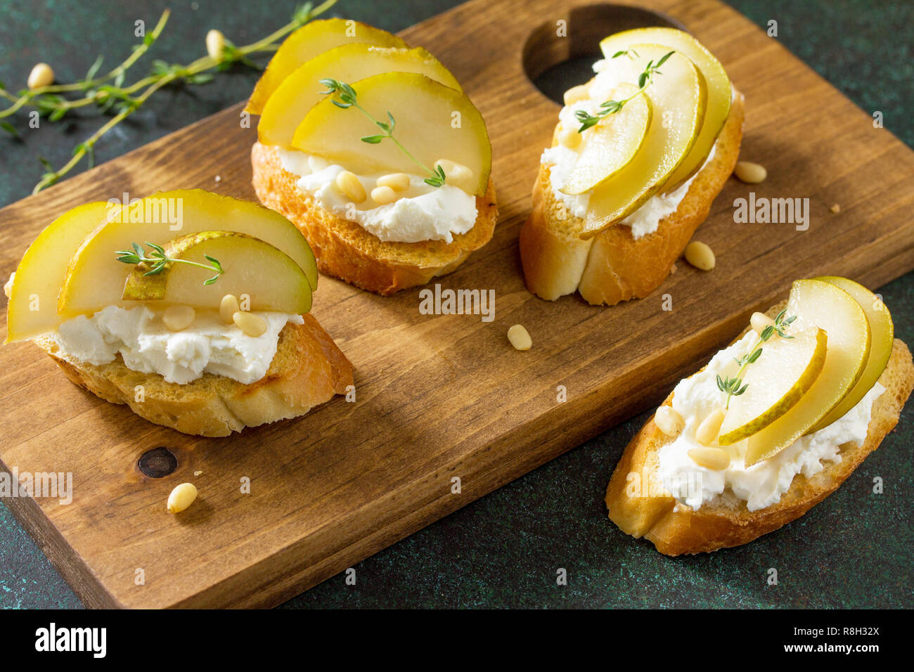 Antipasti des collations pour le vin. Brushetta avec fromage et poire servi sur une planche en bois rustique sur une table en pierre. Banque D'Images