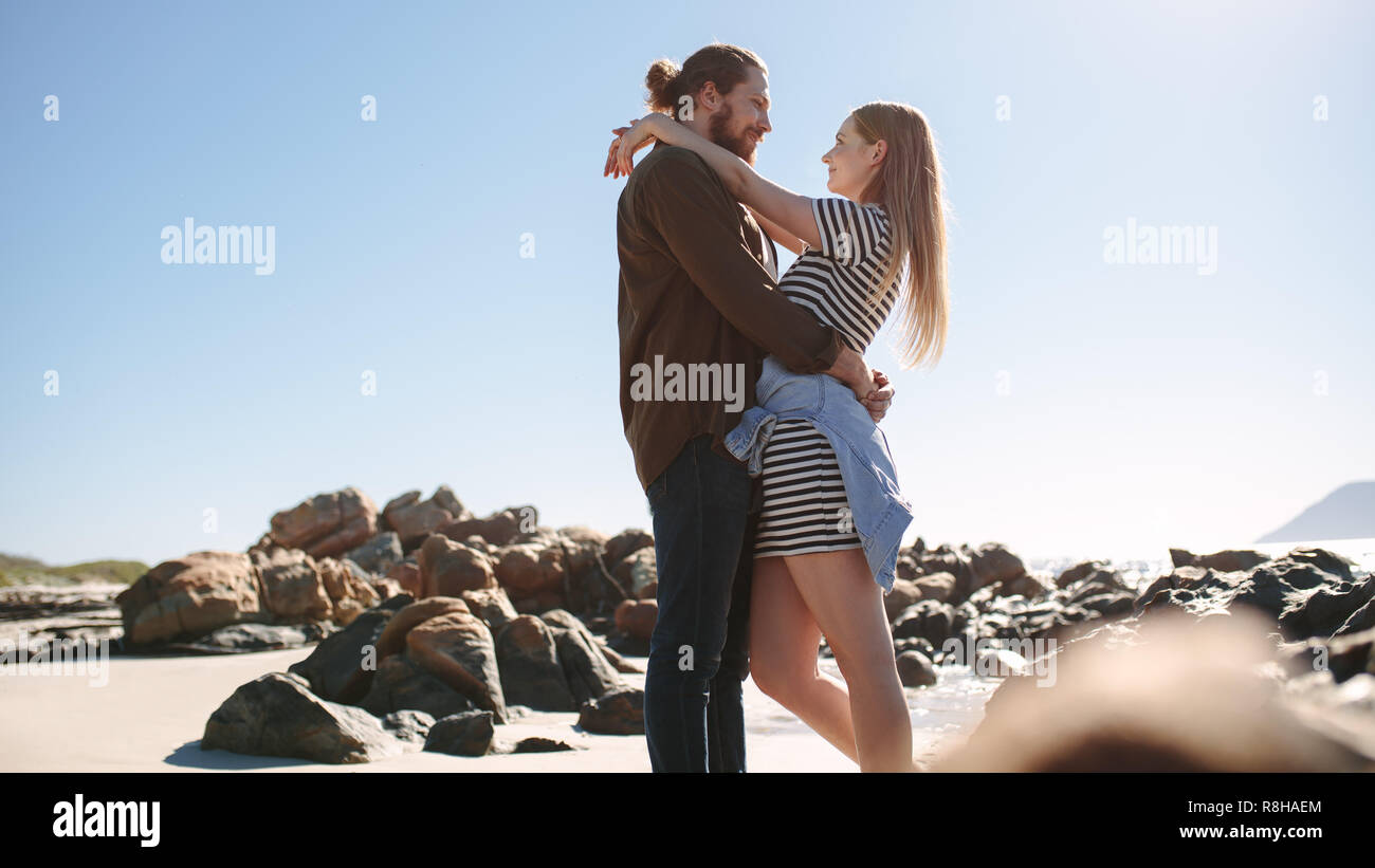Couple romantique sur la plage de rochers. L'homme et la femme se tenant ensemble et se regarder avec amour. Banque D'Images