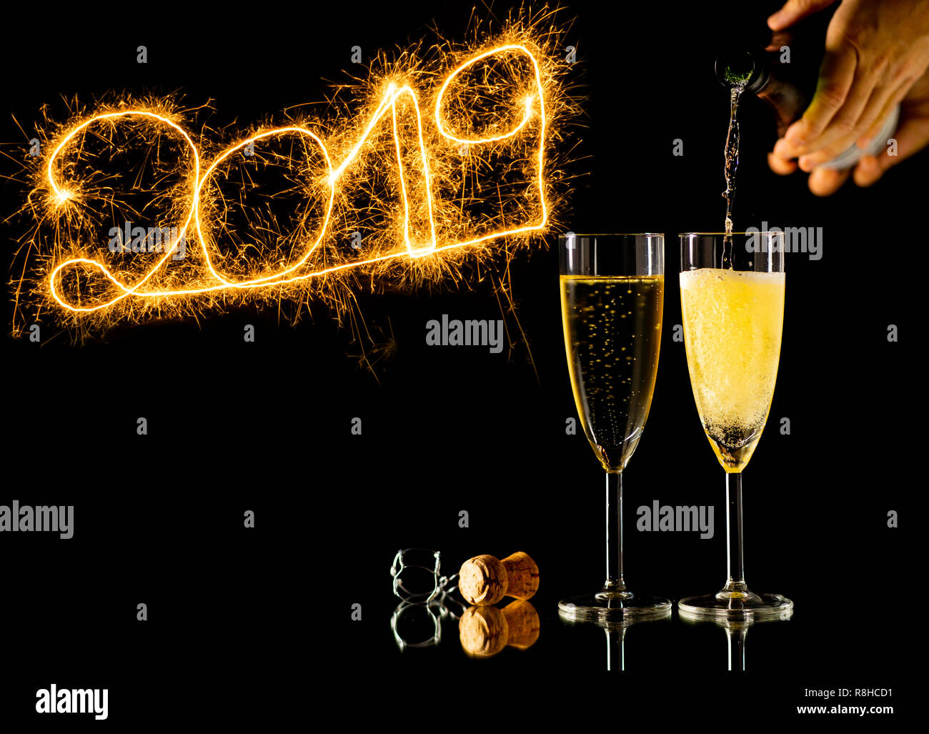 Bonne année deux verres de champagne et de beaux numéros d'or brillant 2019 écrit avec l'éclat d'artifice isolé sur fond noir dans la région de New Y Banque D'Images