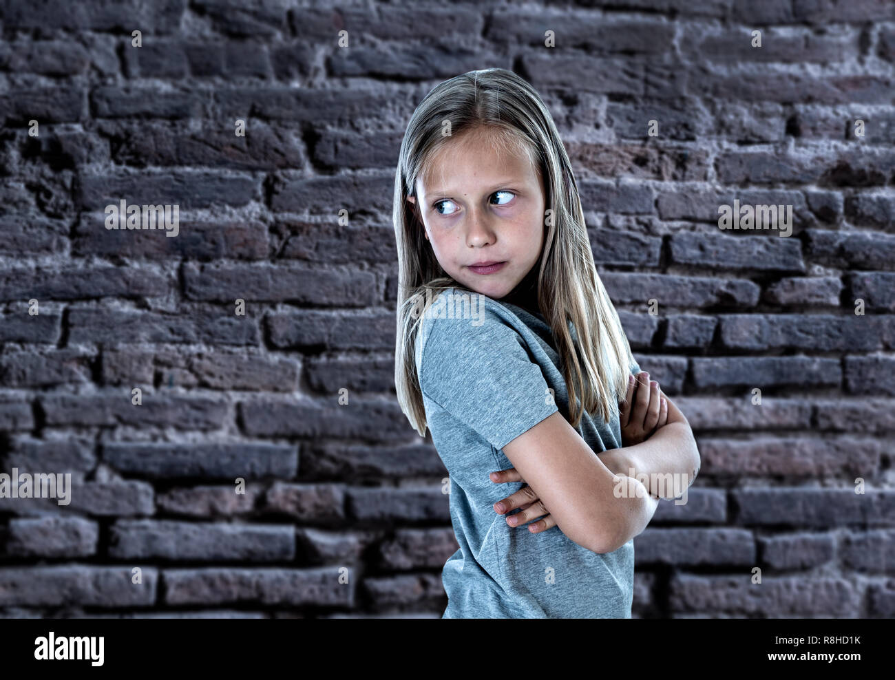 Jeune fille souffrant de l'intimidation et du harcèlement à la peur sur l'abattage de l'épaule seul déprimé et désespéré isolé sur fond mur de brique à l'al. Banque D'Images