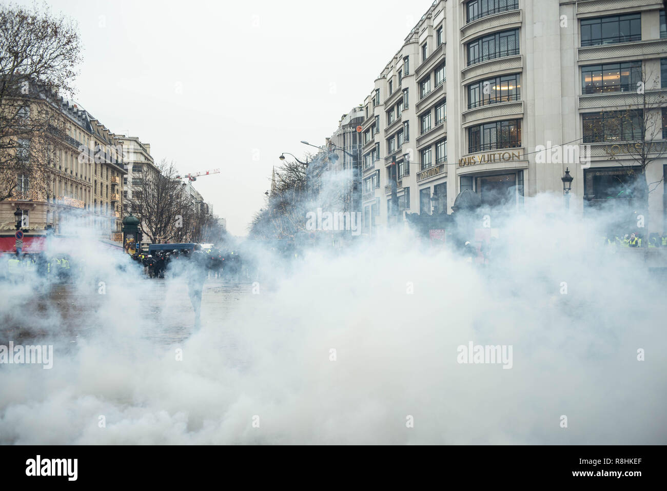 Paris, France. 15 décembre 2018. Des nuages de gaz lacrymogènes remplir la  rue en face de la boutique Louis Vuitton. Gilet jaune (Gilet jaune)  manifestation sur les Champs-Elysées, Paris, le 15 décembre