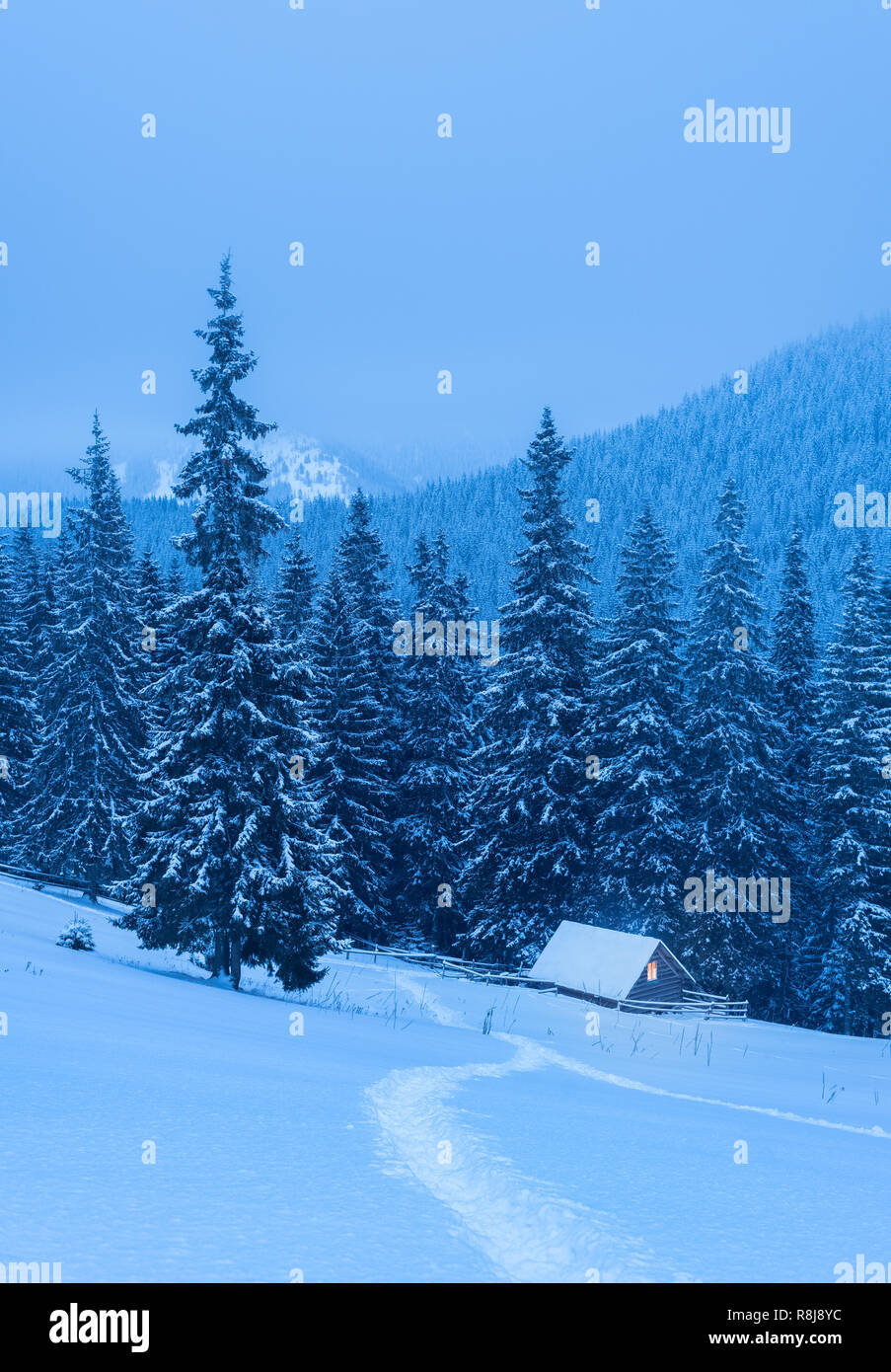 Paysage d'hiver avec une maison en bois dans une forêt de montagne Banque D'Images