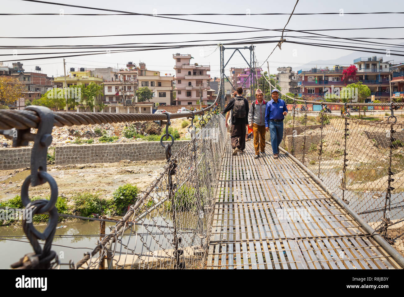 Les hommes de marcher sur un pont suspendu au-dessus de la rivière Bagmati à Katmandou, Népal Banque D'Images