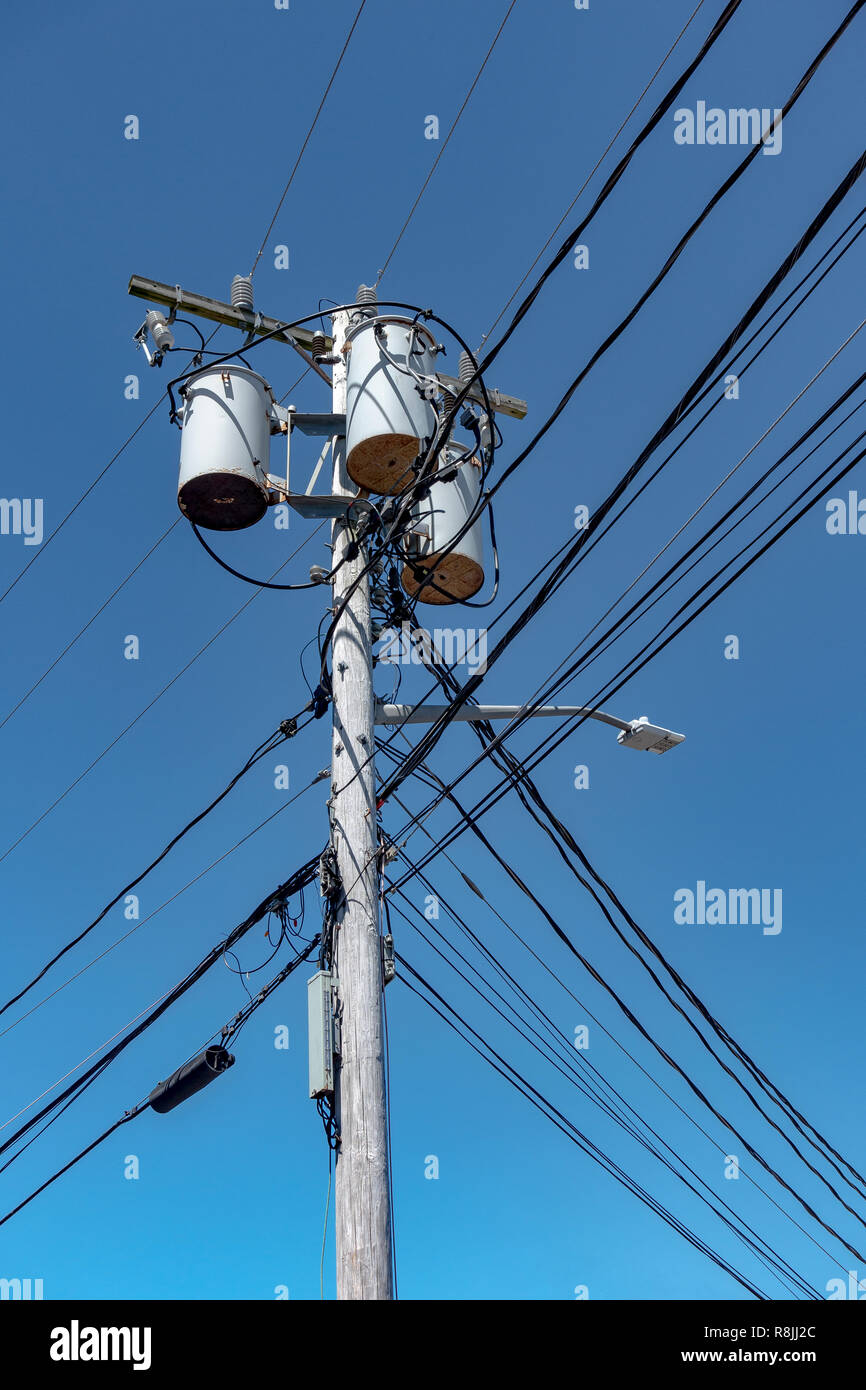 Poste d'alimentation électrique pile de bois et ligne téléphonique terrestre dans la banlieue de villages avec trois transformateurs avec ciel bleu Banque D'Images