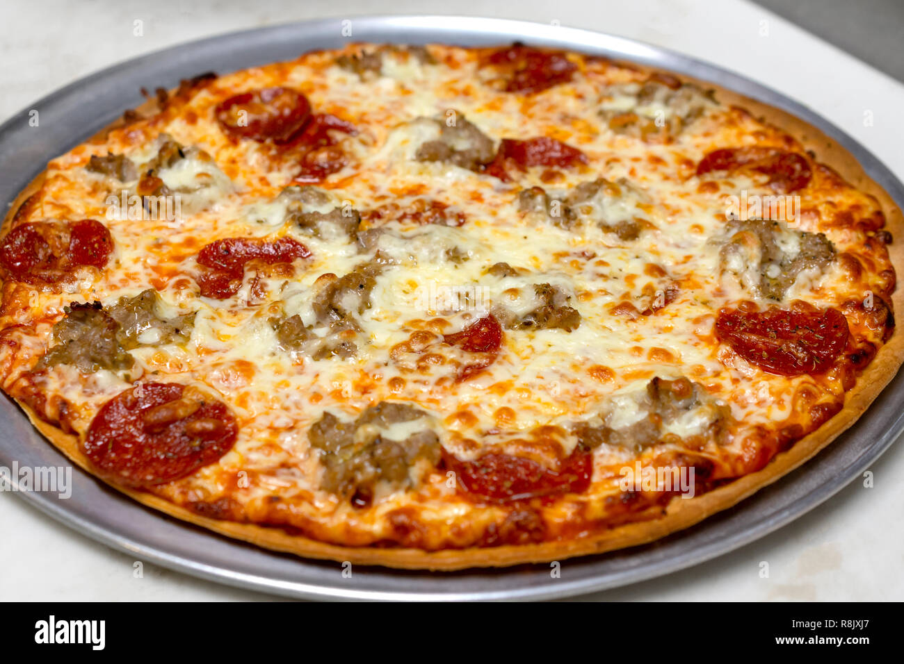 Et saucisse pepperoni pizza fraîchement sorti du four. Pas couper. Ensemble du four. Préparé dans un restaurant. Banque D'Images