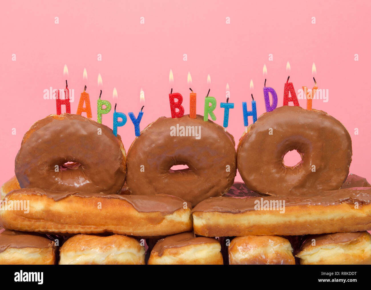 Close Up Sur Le Chocolat Couverts Donuts Empiles Avec Joyeux Anniversaire Bougies Sur Le Dessus Sur Fond Rose Les Amateurs De Beignets Gateau D Anniversaire Photo Stock Alamy