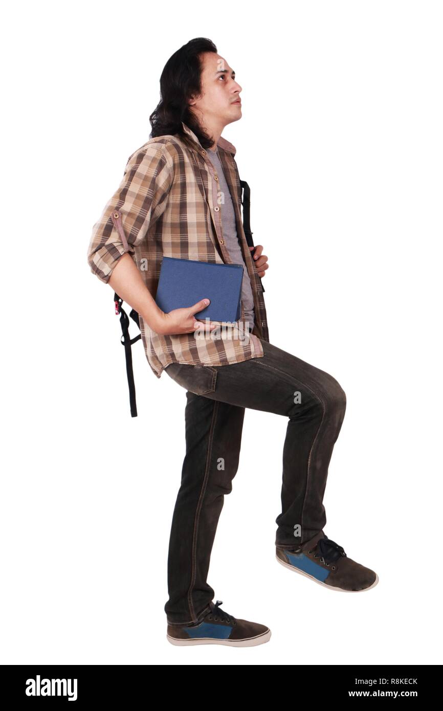 Photo image portrait of a cute Young Asian male student with long hair, looking up et aller de l'avant tout en maintenant des livres, isolated on white Banque D'Images